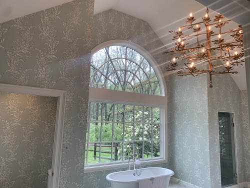A bathroom with a chandelier and grey colored wallpaper